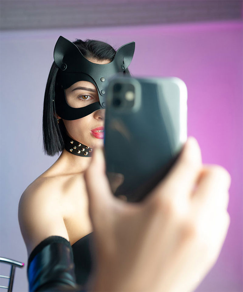 Frau mit Katzenmaske macht Selfie